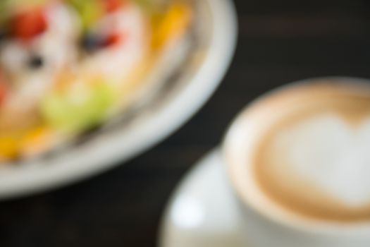 Blurring Heart Shape Froth Milk Latte Art in White Coffee Cup with Dessert on Black Wood Table. Heart shape froth milk Latte art hot beverage for coffee lover