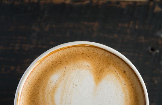 Flatlay Half Bottom Heart Shape Froth Milk Latte Art in White Coffee Cup on Black Wood Table. Heart shape froth milk Latte art hot beverage for coffee lover