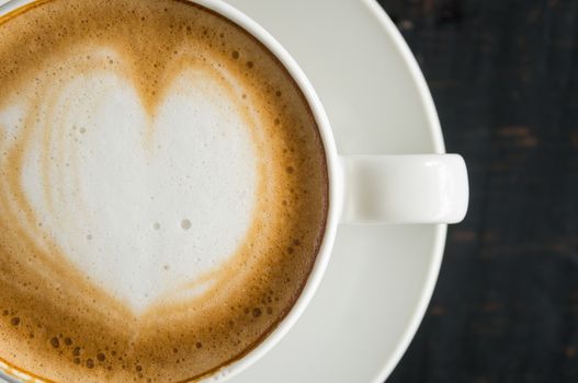 Flatlay Half Heart Shape Froth Milk Latte Art in White Coffee Cup on Black Wood Table. Heart shape froth milk Latte art hot beverage for coffee lover