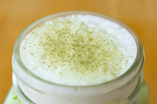 Cold Matcha Green Tea Beverage and Milk Froth and Green Tea Powder Topping in Close Up View