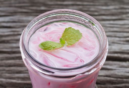 Pink Cold Milk Beverage or Cold Drinks and Peppermint Normal View. Pink cold drinks and ice on wood table for drink