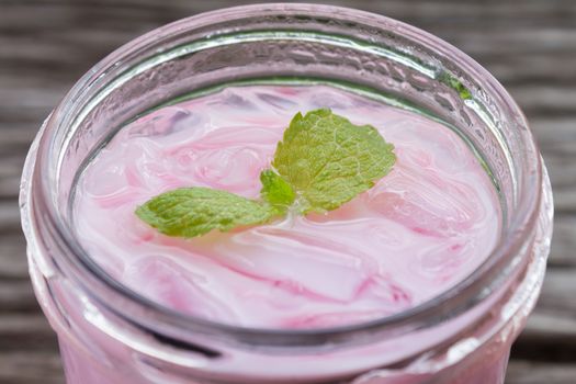 Pink Cold Milk Beverage or Cold Drinks and Peppermint Zoom View. Pink cold drinks and ice on wood table for drink