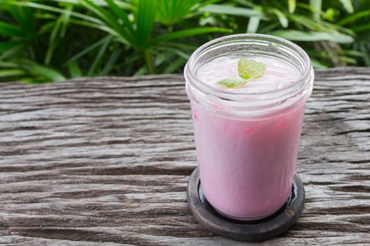 Pink Cold Milk Beverage or Cold Drinks and Peppermint Right Frame. Pink cold drinks and ice on wood table for drink