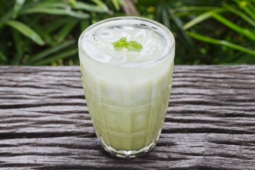 Cold Green Tea Milk Beverage or Cold Drinks Center Frame. Green cold drinks and ice on wood table for drink