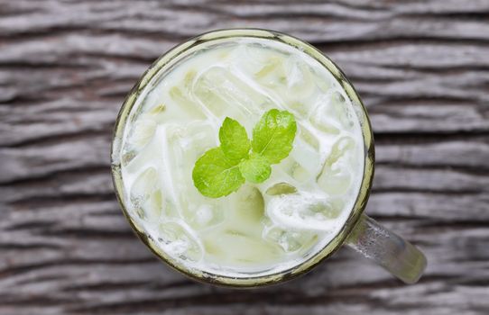 Cold Green Tea Milk Beverage or Cold Drinks Flatlay Center Frame. Green cold drinks and ice on wood table for drink