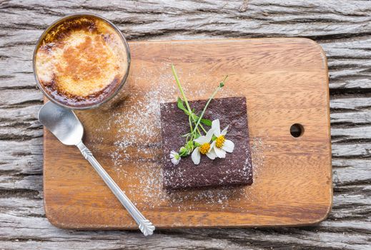 Daisy Flower on Chocolate Brownie Cake with Latte Coffee on Chopping Board or Cutting Board on Wood Table Flatray or Top Table Angle. Relax coffee break time in 
coffee shop right frame