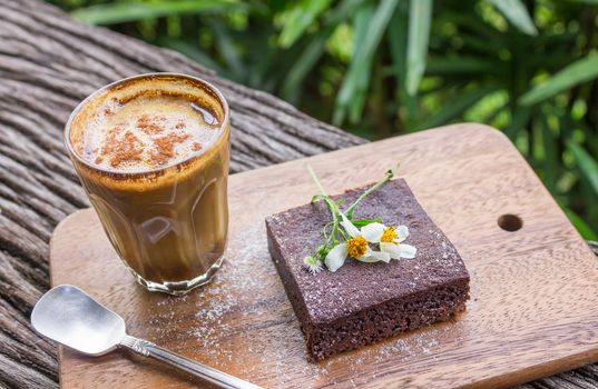 Latte Coffee and Chocolate Brownie Cake on Cutting Board on Wood Table on Tree Background. Latte coffee break time for food and drink category