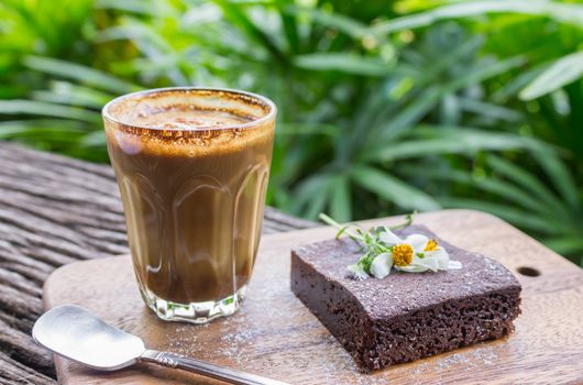 Latte Coffee and Chocolate Brownie Cake on Cutting Board on Wood Table on Tree Background. Latte coffee break time for food and drink category