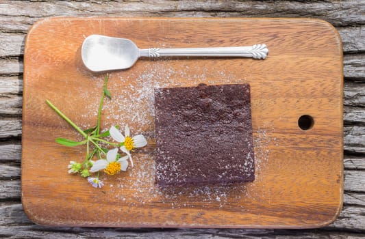 Chocolate Brownie Cake and Daisy Flower and Spoon on Chopping Board or Cutting board on Wood Table in Flatray or top table angle