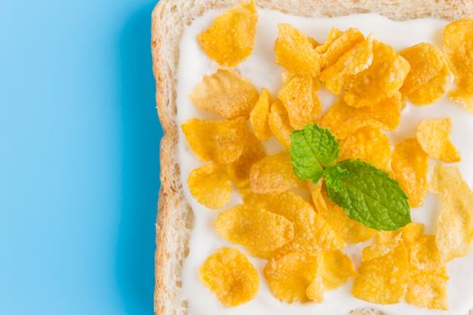 Cornflakes on Yogurt on Bread with Peppermint on Blue Pastel Background Flatlay Close Up. Cereal Breakfast bread healthy clean food for food and dessert category