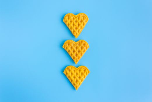 3 Pieces Heart Shape Waffle in Vertical on Blue Pastel Background Minimalist Style. Heart shape waffle dessert in minimalist style for food and dessert category