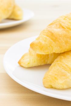 Croissant or bread or bakery on white dish on wood table portrait view