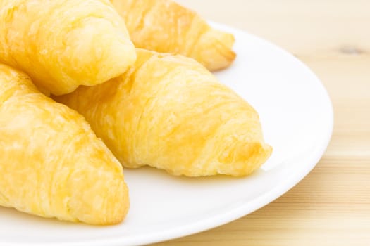 Croissant or bread or bakery on white dish on wood table close up view