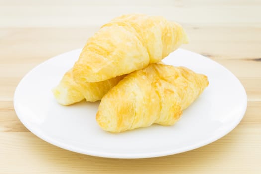 Croissant or bakery or bread on white dish on wood table