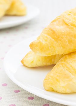 Croissant or Bread or Bakery on White Dish on pink point placemat close up view