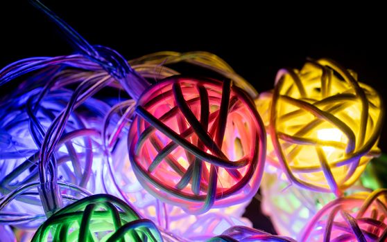 Colorful Christmas Lights String on Black Background. Christmas Lights String in Rattan Ball Shape on Black Scene.