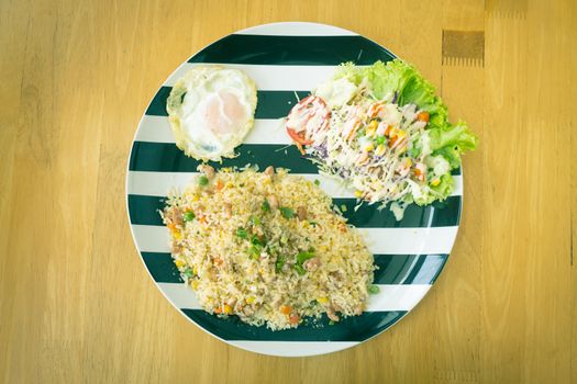 Thai Sour Pork Fried Rice and Salad and Fried Egg in Dish on Wood Table on Top View or Flatlay View in Vintage Tone