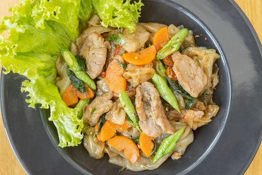 Stir Fried Noodle and Pork and Carrot and Yardlong Beans and Lettuce with Black Soy Sauce on Top View with Natural Light in Center Frame