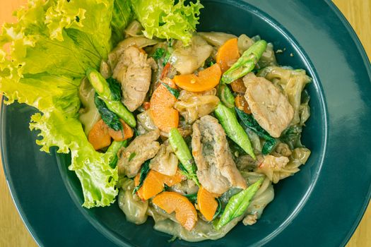 Stir Fried Noodle and Pork and Carrot and Yardlong Beans and Lettuce with Black Soy Sauce on Top View with Natural Light in Center Frame in Vintage Tone