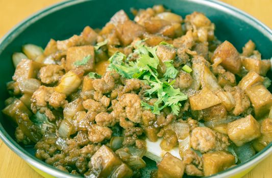 Stir Fried Pork with Onion and Garlic and Black Soy Sauce and Coriander Topping and Tofu in Pan on Wood Table with Natural Light in Zoom View in Vintage Tone