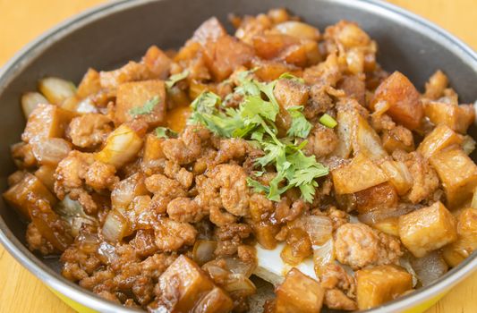 Stir Fried Pork with Onion and Garlic and Black Soy Sauce and Coriander Topping and Tofu in Pan on Wood Table with Natural Light in Zoom View