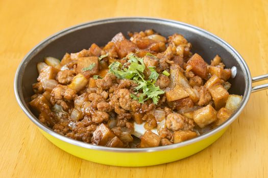 Stir Fried Pork with Onion and Garlic and Black Soy Sauce and Coriander Topping and Tofu in Pan on Wood Table with Natural Light