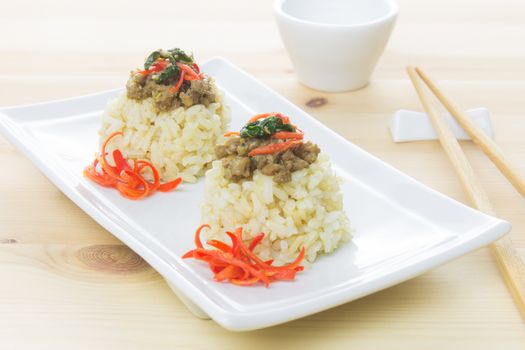 Salted pork with chili & Basil leaves on white rectangle dish and chopsticks and small white cup. Thai food on wood table.