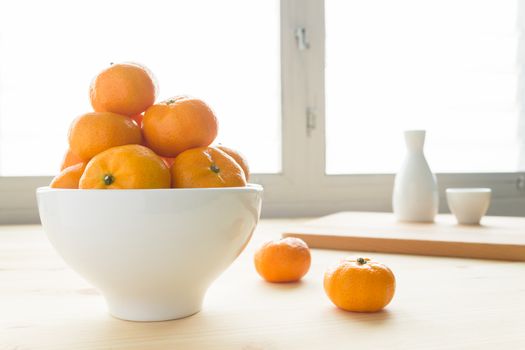 Mandarin or chinese orange or tangerine or small orange in white bowl on wood table and tea cup