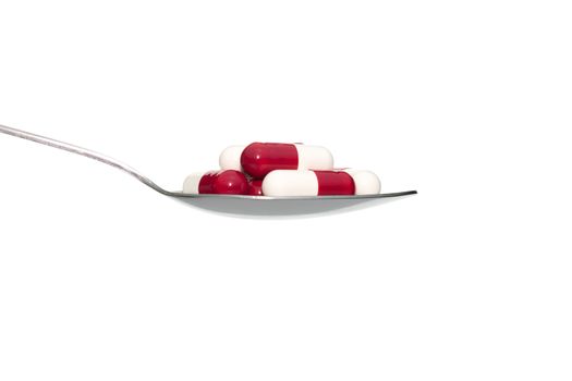 Red white drug or pill or vitamin on metal Spoon isolated on white background. Concept about health care or medical or science including food concept.