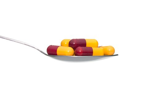 Red yellow drug or pill or vitamin on metal Spoon isolated on white background. Concept about health care or medical or science including food concept.