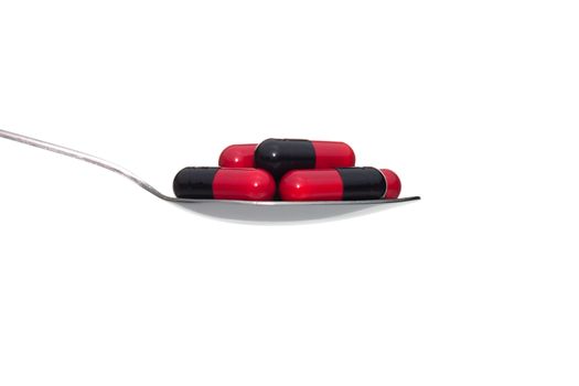 Black red drug or pill or vitamin on metal Spoon isolated on white background. Concept about health care or medical or science including food concept.