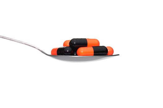 Black orange drug or pill or vitamin on metal Spoon isolated on white background. Concept about health care or medical or science including food concept.