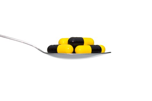 Black Yellow drug or pill or vitamin on metal Spoon isolated on white background. Concept about health care or medical or science including food concept.