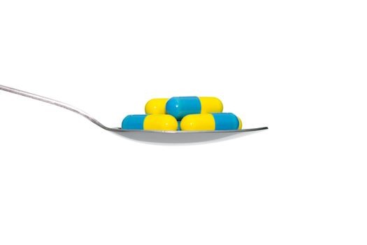 Blue Yellow drug or pill or vitamin on metal Spoon isolated on white background. Concept about health care or medical or science including food concept.