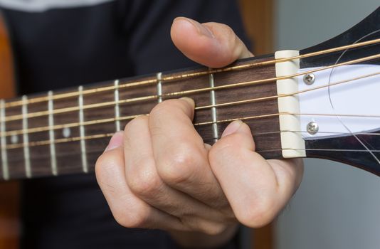Guitar Player Hand or Musician Hand in A Minor Chord on Acoustic Guitar String with soft natural light in close up view