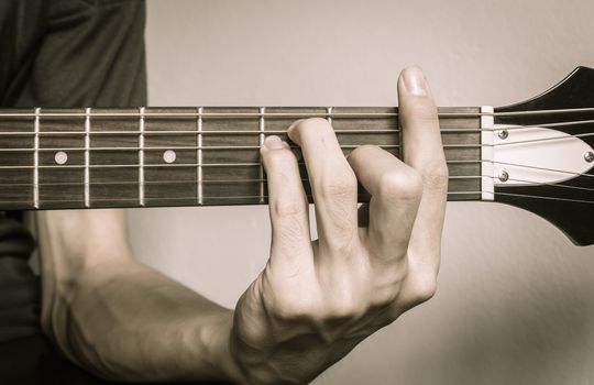 Guitar Player Hand or Musician Hand in F Major Chord on Acoustic Guitar String with soft natural light in close up view