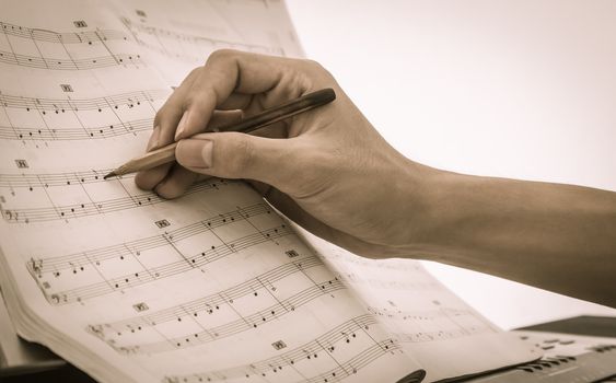 Hand of Piano Player is Writing Notes on Piano Staff or Sheet Music by Old Pencil