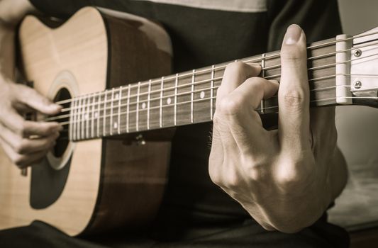 Guitar Player Hand or Musician Hand in F Major Chord on Acoustic Guitar String with soft natural light in side view