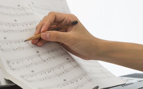 Hand of Piano Player is Writing Notes on Piano Staff or Sheet Music by Old Pencil