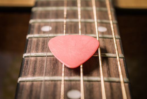Red Pick on Acoustic Guitar String and Fingerboard or Fretboard in Zoom view