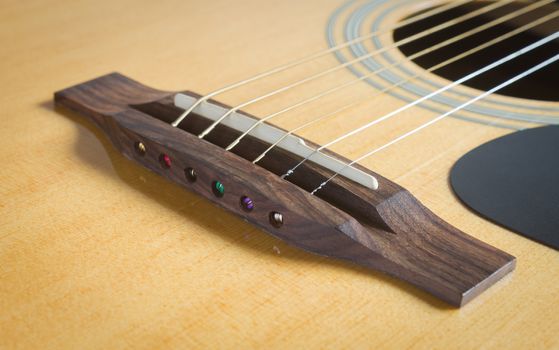 Wood Bridge and Saddle and Pickguard and Sound Hole with Acoustic Guitar String in Natural Light