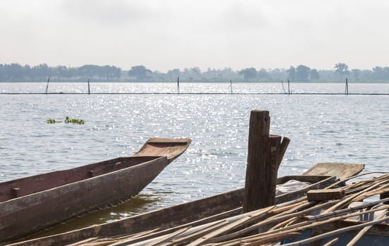 Wood Fishing Boat or Rowboat on Swamp with Wood Boat Pole. Wood fishing boat or rowboat or gondola of villagers stop at harbor or port. Wood fishing boat for tradition or culture 
scene with tree and bamboo