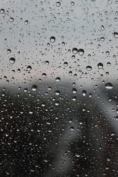 Drops of rain on the window, rainy day, dark tone. Shallow DOF