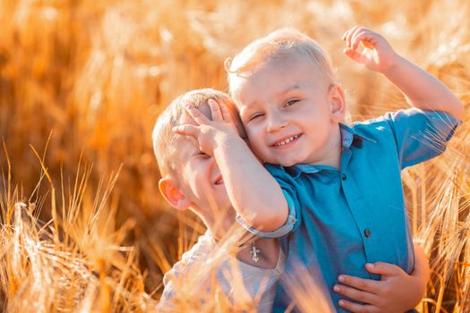 Cute little kids having fun in golden wheat field at the sunset