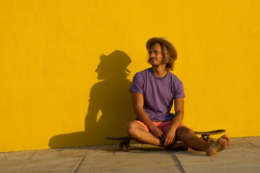 Young blond man with summer clothes, hat and sunglasses enjoying the summer