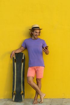 Young blond man with summer clothes, hat and sunglasses enjoying the summer and talking with the mobile phone