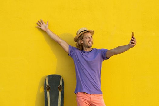 Young blond man with summer clothes, hat and sunglasses enjoying the summer and talking with the mobile phone