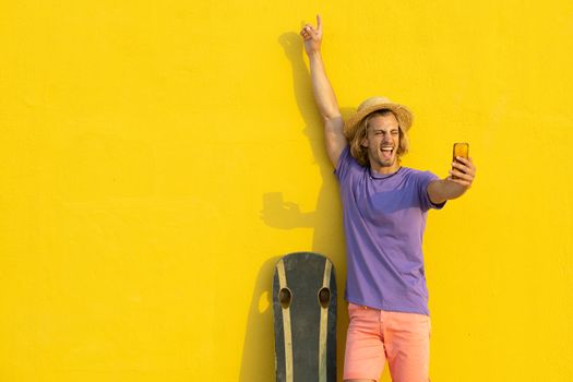 Young blond man with summer clothes, hat and sunglasses enjoying the summer and talking with the mobile phone