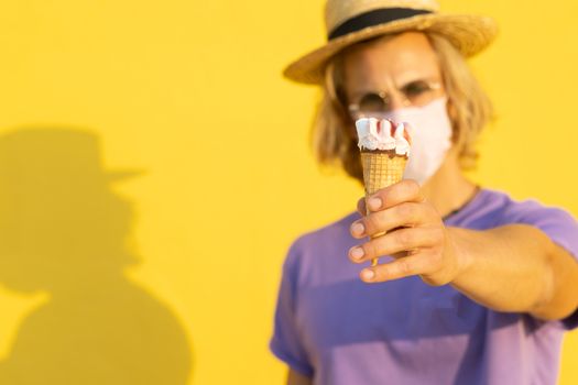 Young blond man with summer clothes, hat and sunglasses enjoying the summer with an ice cream