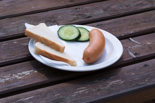 Bock sausage, wieners or Frankfurther sausage with toast and cucumbers on a white plate.